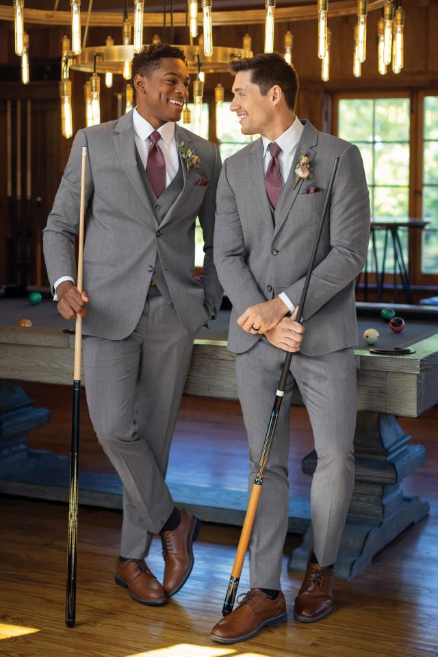 two men wearing Michael Kors Medium Grey Performance Suit and wine colored ties standing in front of a pool table with pool cues in hand.